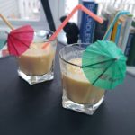 Two glasses with umbrellas and straws filled with smoothie