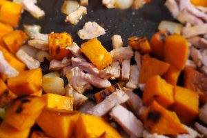 Sweet potato cubes, chopped onions, and thinly sliced pork sauteing